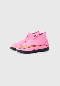 Rosa treningssko med en glatt, teksturert overdel, svart gummisåle og oransje akzentstripe. Har slip-on-design og drahåndtak.
