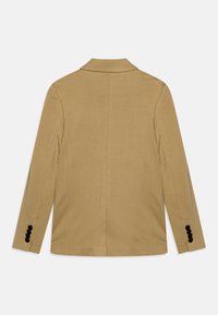 Beżowa marynarka z klapami z wycięciem, pojedynczym rozcięciem z tyłu i trzema czarnymi guzikami na każdym mankiecie. Gładka faktura i dopasowany krój.