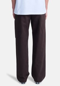 Pantalones de pierna ancha negros hechos de algodón, con una textura suave y un corte holgado, combinados con zapatillas equipadas con acentos estampados.