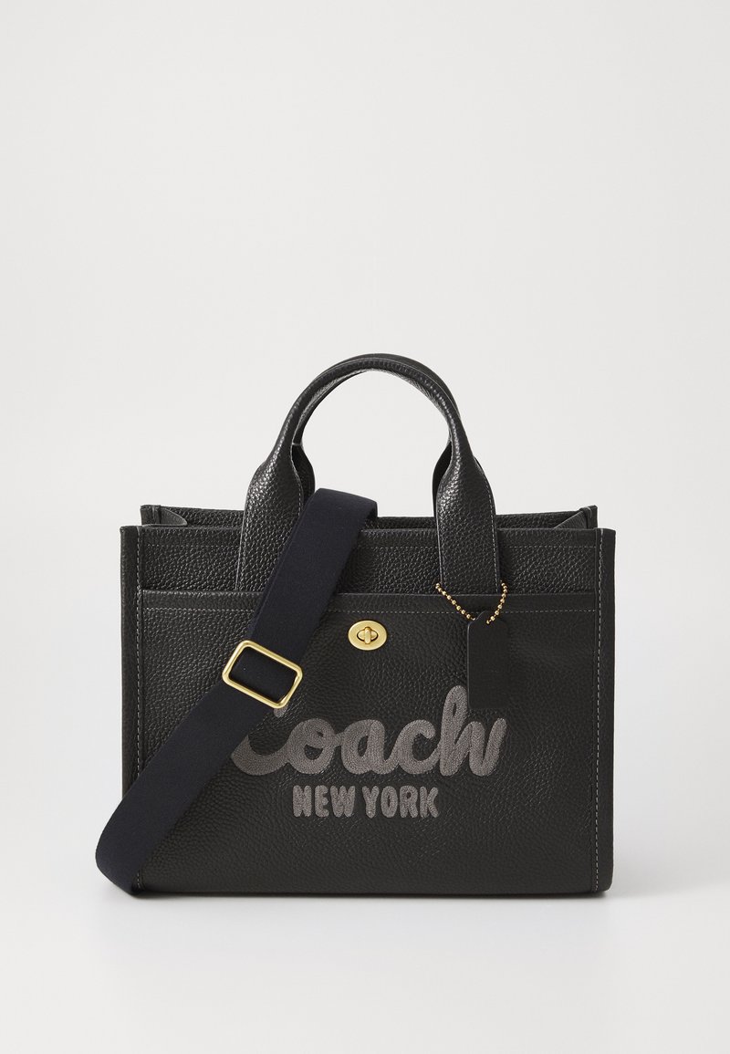 Musta nahkainen käsilaukku, jossa on tekstuuri, varustettuna "Coach New York" -tekstillä harmaalla värillä, tuplakahvoilla ja irrotettavalla olkahihnalla. Kultainen metalliosuus.