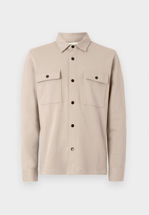 Beige button-up shirt with a collar, four front pockets, and black buttons. Made of soft fabric with a smooth texture and long sleeves.
