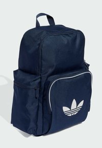 Granatowy plecak wykonany z trwałego materiału, z przednią kieszenią na zamek, białym logo oraz kontrastowym obszyciem wzdłuż głównej komory.