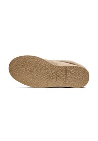 Licht beige schoenzool met een gestructureerd oppervlak, met een ronde vorm en een reliëf logo-detail. Gladde randen en een minimalistisch ontwerp.