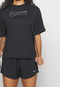 Svart Nike-t-shirt med en vit logotyp, kombinerad med svarta sportshorts. Kortärmad, avslappnad passform och med en mjuk textur.