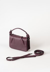 Piccola borsa a tracolla in pelle viola con manico annodato e cinturino lungo staccabile, posizionata su uno sfondo bianco.