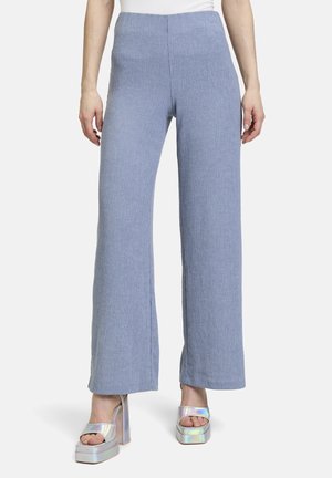 Helleblaue, weit geschnittene Hose aus strukturiertem Stoff mit hohem Bund. Kombiniert mit metallischen Plateau-Schuhen.