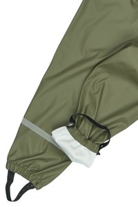 Wasserabweisende grüne Hose mit elastischen Bündchen, ausgestattet mit einer weißen Aufbewahrungstasche, die mit einem schwarzen Riemen und einem reflektierenden grauen Streifen befestigt ist.