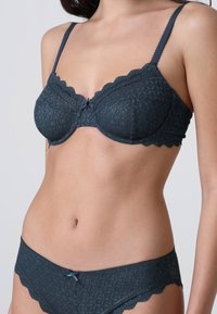 Reggiseno in pizzo blu scuro con un motivo geometrico, bordi a scallop e spalline regolabili, abbinato a mutandine con rifinitura in pizzo coordinate.
