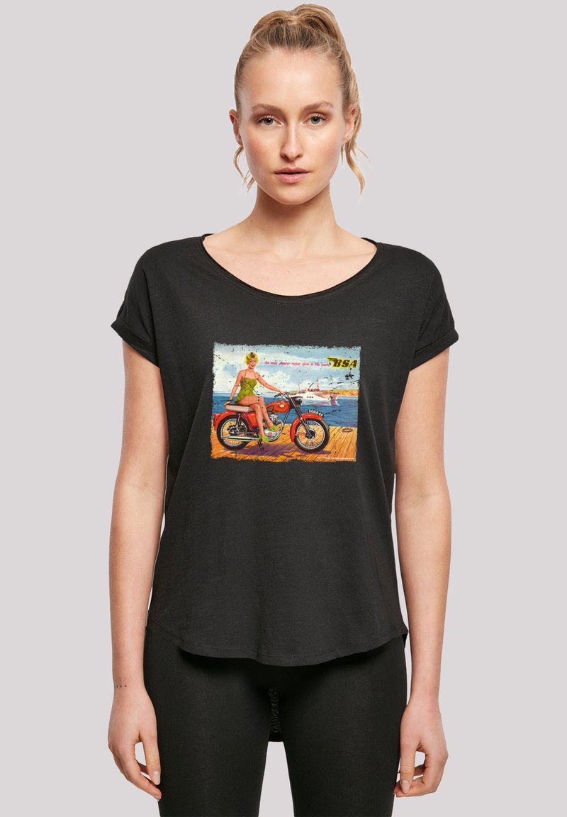 Schwarzes T-Shirt mit kurzen Ärmeln und einem bunten Retro-Druck, der eine Frau auf einem Motorrad vor einer Strandkulisse zeigt. Weicher Stoff, lockere Passform.