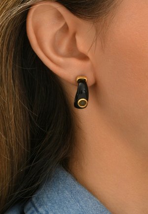 Boucles d'oreilles en forme de goutte noires avec un accent doré en haut et un détail circulaire en bas, texture lisse avec une finition brillante.