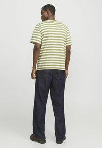 Grøn- og hvidstribet t-shirt, afslappet pasform, med korte ærmer. Sammen med mørkeblå jeans og sorte sko. Simpelt design og afslappet look.