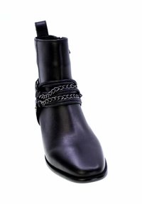 Stivale alla caviglia in pelle nera con punta affusolata, caratterizzato da una catena decorativa attorno alla parte centrale e un pratico tassello sul retro.