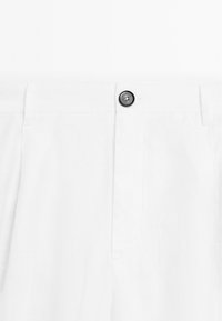 Bílé lněné kalhoty s rovním předním dílem, s jedním černým knoflíkovým zapínáním a bočními kapsami. Hladká textura a detaily přizpůsobeného střihu.