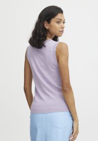 Top senza maniche di colore viola in maglia con scollatura tonda, silhouette aderente e orlo a coste, abbinato a pantaloni leggeri blu chiaro con texture.