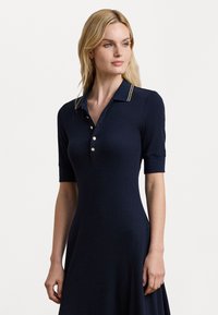 Ναυτική πόλο φόρεμα με κοντά μανίκια, ριγέ υφή, χρυσά κουμπιά και γιακά με αντίθετες ρίγες.