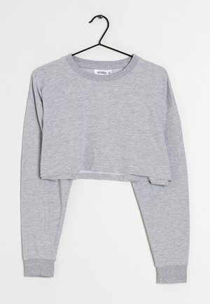 Sudadera gris corta con mangas largas, hecha de suave tela de algodón. Tiene un cuello redondo y puños acanalados, colgada en un gancho negro.