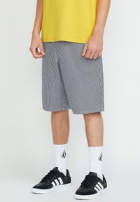 Striped shorts in navy and white, featuring a relaxed fit, side pockets, and a straight hem, paired with black sneakers and white socks.
