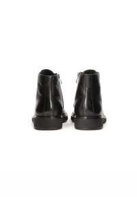 Botas de tobillo de cuero negro con una textura suave, con cierre de cremallera en la parte trasera y un tacón bajo, sólido y negro.