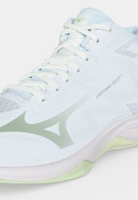 Бяло и светлозелено спортно обувки с връзки, лого на Mizuno и текст "Lightning Select" отстрани.