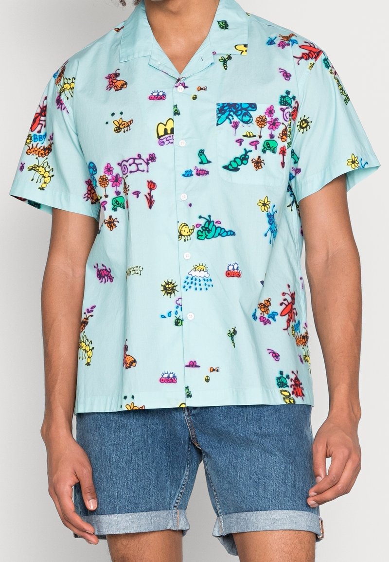 Camicia a maniche corte in cotone blu chiaro con stampe colorate e giocose di insetti e fiori; presenta una tasca sul petto e chiusura con bottoni.
