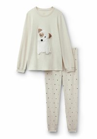 Beige pyjama set met een longsleeve top met een gestructureerde witte hondenapplicatie en een broek met polka dots in lichtcrème met zwarte hartjes.