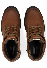 Bottes de cheville en cuir marron avec bout rond, design à lacets, intérieur rembourré et semelle en caoutchouc. Étiquette "Camel Active" visible à l'intérieur.