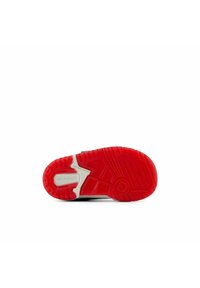 Puntti punainen ja valkoinen New Balance -kengän pohja, jossa on teksturoitu pito, ja "ei jättäviä merkkejä" -label näkyy valkoista taustaa vasten.