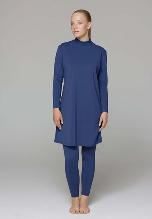 Tunique bleue à manches longues avec un col haut, accompagnée de leggings bleus assortis ; texture lisse et coupe fluide, conçue pour le confort.