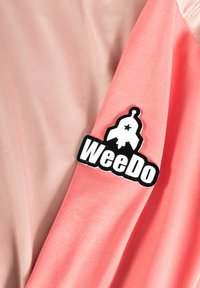 Rosa und korallenfarbene Stoffmischungen mit einem großen schwarzen "WeeDo"-Logo und einem Raketen-Design. Glatte Textur mit leichtem Glanz.