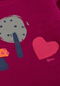 Camicia di cotone fucsia con un grafico di un albero grigio e funghi multicolore, con una toppa a forma di cuore rosso e logo del marchio ricamato.
