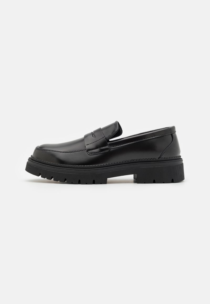 Mocassin en cuir noir avec semelle épaisse rainurée et bride classique pour pièce, présenté en profil latéral sur fond blanc.