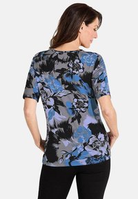 Bloemige shirt met korte mouwen, met een grijze achtergrond en zwarte, blauwe en paarse bloemstructuren. Zachte stof met een ontspannen pasvorm.