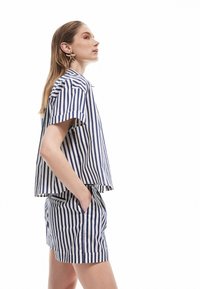 Camisa de algodón de manga corta a rayas en azul marino y blanco combinada con pantalones cortos a juego; presenta rayas horizontales y verticales, corte casual y bolsillos.