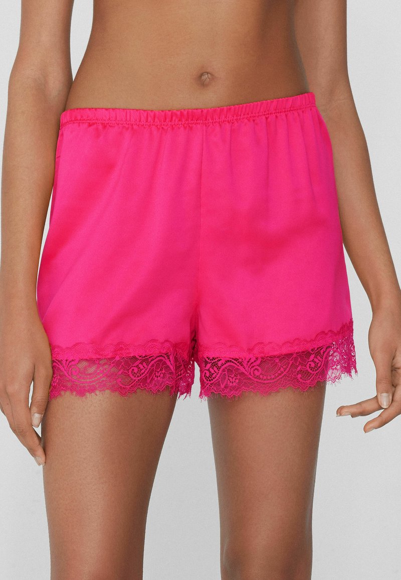 Roze satijnen shorts met een losse pasvorm, voorzien van een kantafwerking aan de zoom. De tailleband is elastisch voor comfort.