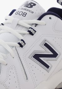 White New Balance 608 sneaker with navy logo, white laces, and perforated leather detailing on the side and tongue.