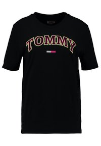 Camiseta de algodón negra de manga corta. Presenta 'TOMMY' en letras negritas y coloridas, con un pequeño gráfico de bandera en rojo, blanco y azul.