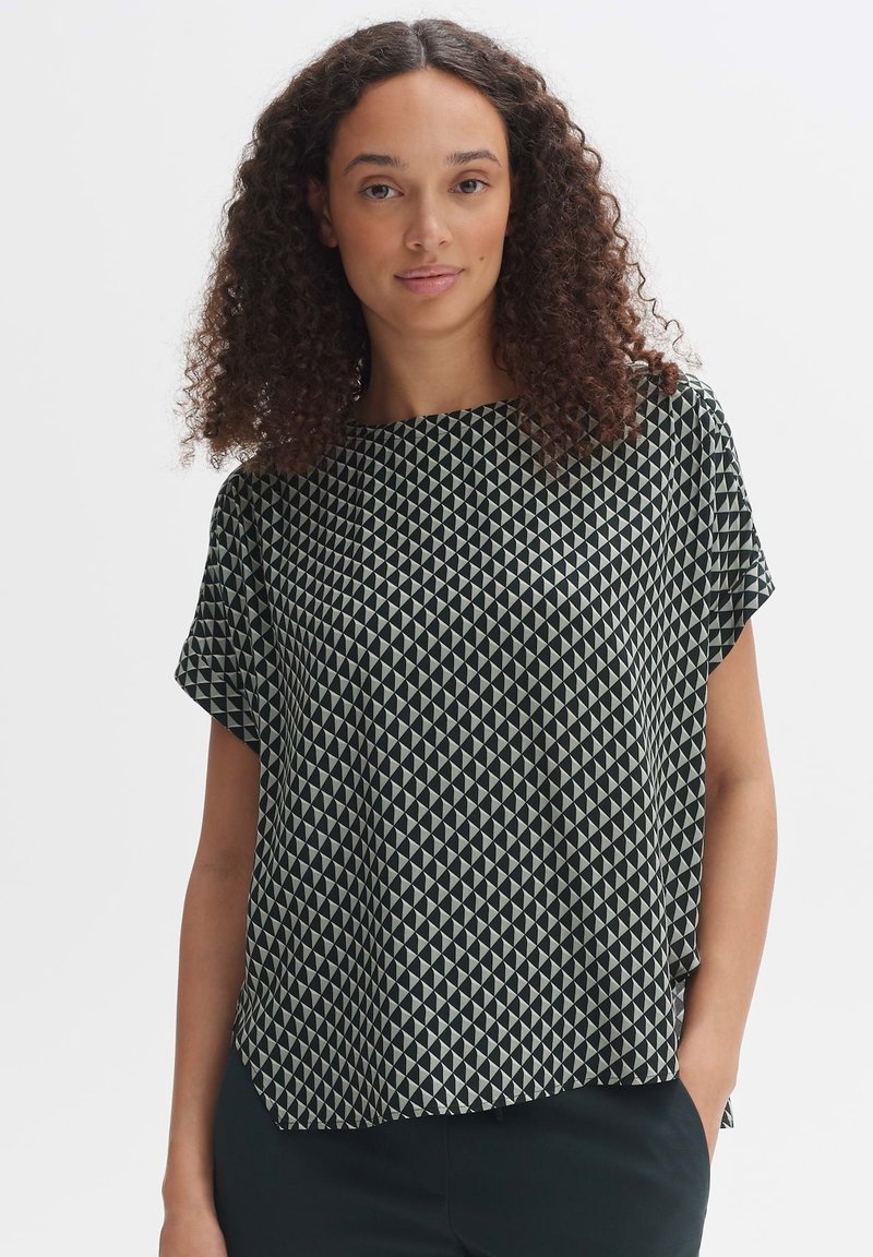 Top nero a maniche corte con un motivo geometrico di triangoli color crema. Tessuto leggero con una vestibilità rilassata e scollo rotondo.