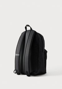 Μαύρο σακίδιο με επενδεδυμένα πάνελ, κομψό σχέδιο και ανώτερη λαβή. Διαθέτει πλαϊνή τσέπη και ανακλαστική λωρίδα για ορατότητα.