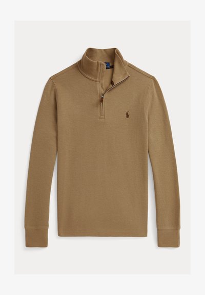 Karamelli värvi kudum, millel on veerandist tõmblukuga krae. Ees on väike tikandiga logo ja soonikuga varrukad. Tekstuuriga kangas.