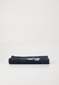Toalha preta dobrada com uma textura suave, apresentando um design gráfico azul de um lado. Forma retangular, aparência minimalista.