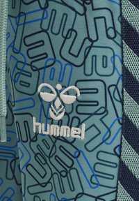 Turkosa träningsshorts med blå geometriska mönster, med en vit broderad logotyp och texturerade mesh-sidpaneler.