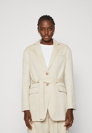 Blazer en lin beige avec une ceinture, deux poches avant et une fermeture à un bouton. Coupe ajustée avec col à revers et manches longues.
