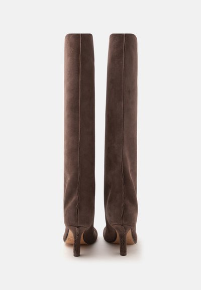 Paire de bottes hautes en daim marron à talons hauts, debout, vue de dos sur un fond blanc uni.