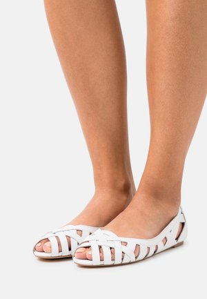 Witte leren platte schoenen met een open teenontwerp, voorzien van gevlochten bandjes en een platte zool. Soepele textuur met uitsnijdingen.