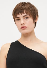 Top de tirantes negro acanalado con un diseño de un solo hombro. Textura suave, forma ajustada y estilo minimalista sin herrajes visibles.