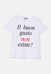 Biała bawełniana koszulka z wyrazistym czarnym napisem i czerwonym akcentem. Napis brzmi „Il buon gusto non esiste!” w różnych grubościach czcionki.