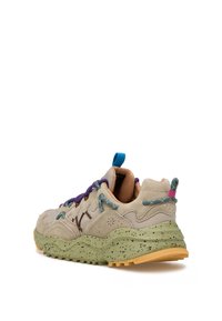 Sneaker beige in suede con suola verde maculata, lacci viola e blu, e linguetta sul tallone turchese. Presenta un design superiore testurizzato.