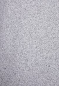 Jasnoszary dzianinowy materiał o miękkiej fakturze i równomiernym wzorze ściegów, z subtelnymi odcieniami i gładkim wykończeniem.