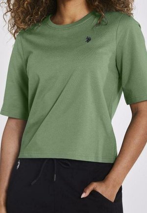 Vihreä puuvillaita paita, jossa on pyöreä kaula-aukko ja lyhyet hihat. Paidassa on pieni tummansininen logo rinnassa ja rento istuvuus.