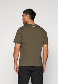 Oliven grøn T-shirt lavet af bomuld, med korte ærmer og rund halsudskæring. "Venum" logo i lys farve nær den øverste rygudskæring.